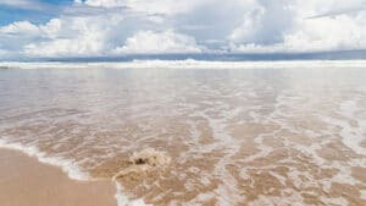 Santa Teresa beach with gentle waves and cloudy sky.