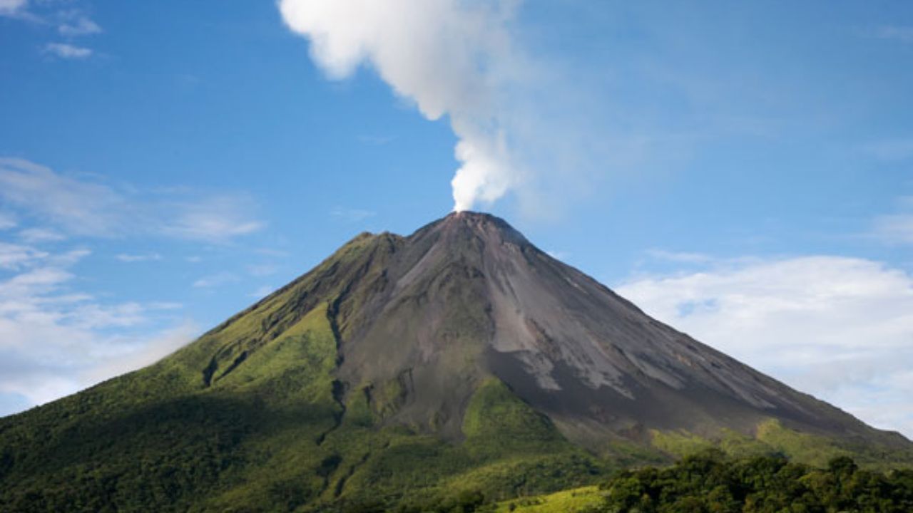  Arenal Volcano in Costa Rica emitting steam above slopes. 