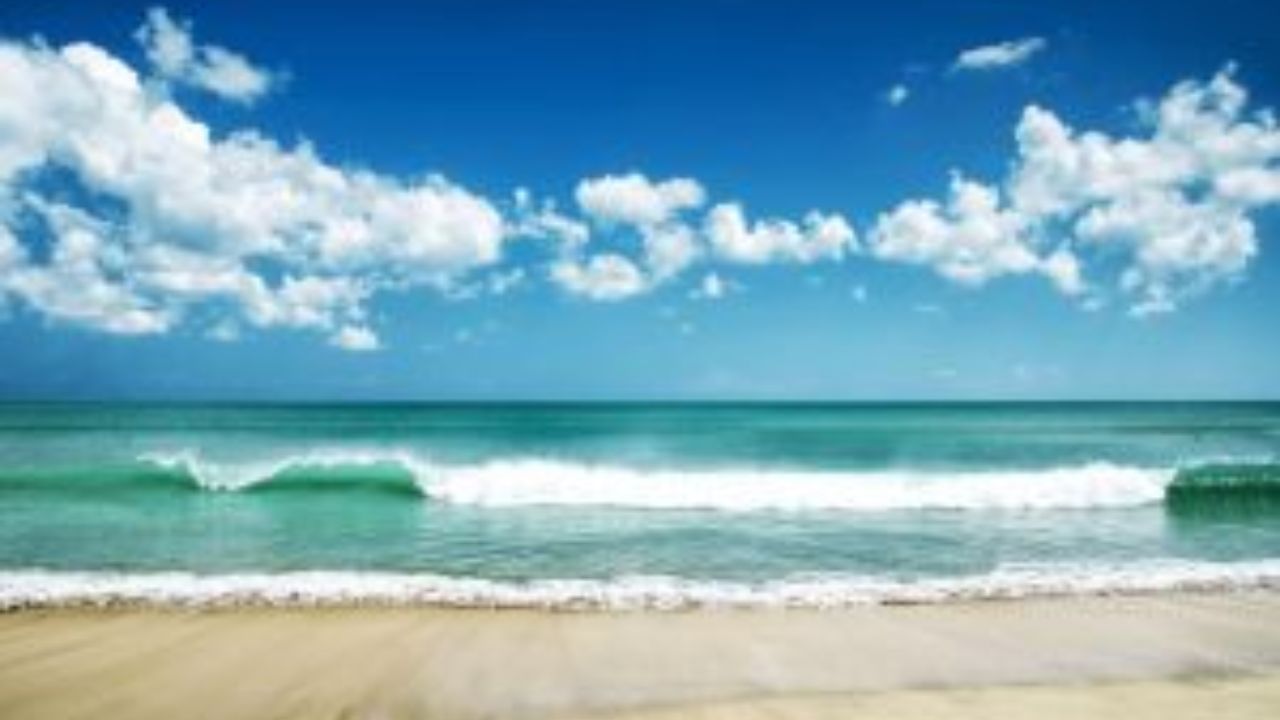 Turquoise Guanacaste beach with waves under bright blue sky. 